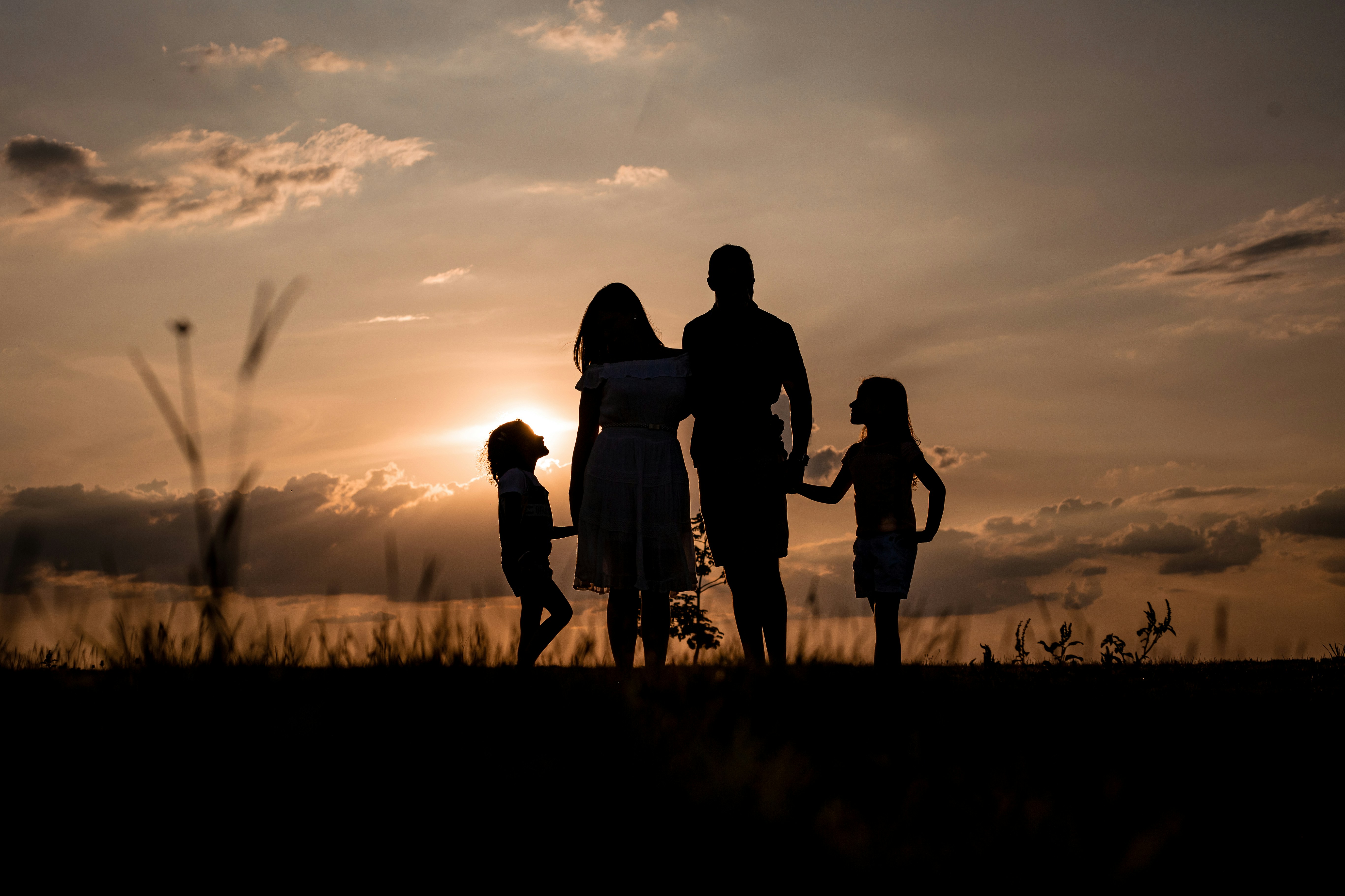 A family standing close together, silhouetted against a golden sunset